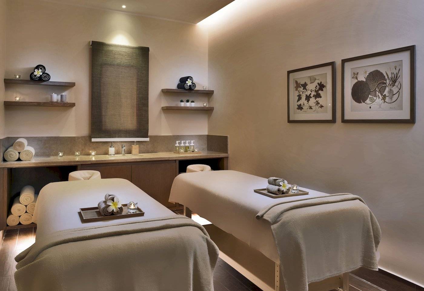 Spa-Behandlungsraum im Jaz Lamaya Resort mit zwei Massagetischen, Kerzen und Pflanzen.
