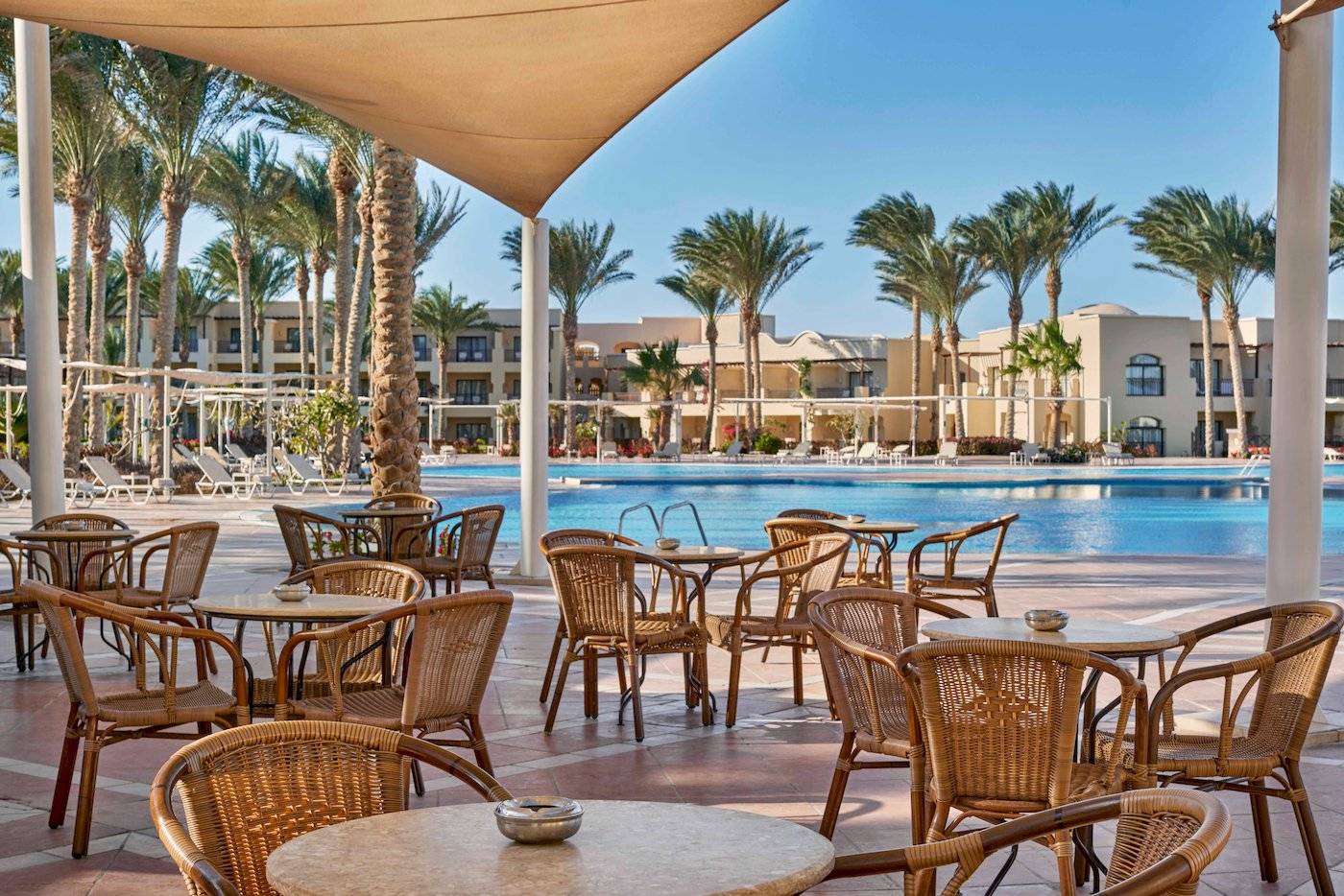 Außenterrasse mit Tischen und Stühlen am Pool im Jaz Lamaya Resort