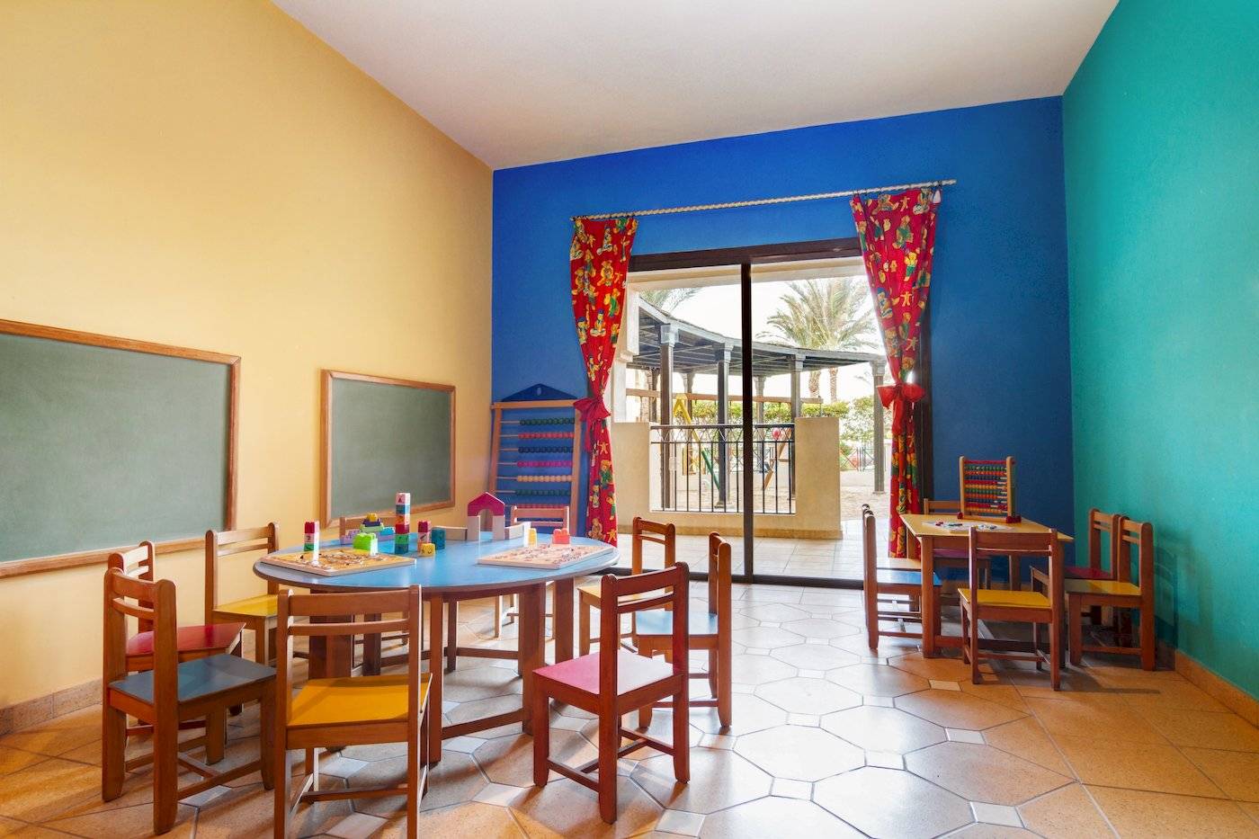 Kinderzimmer im Jaz Lamaya Resort mit bunten Wänden und Spieltischen.