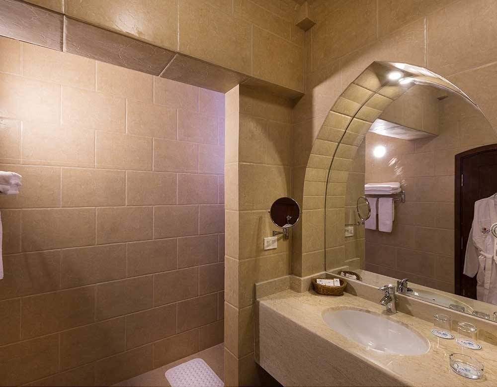 Badezimmer im Utopia Beach Club mit einer Dusche, Waschbecken und Spiegel.