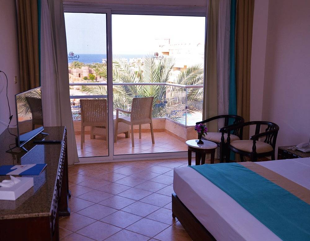 Zimmer im Utopia Beach Club Hotel mit Blick auf das Meer und eine Terrasse mit Möbeln.