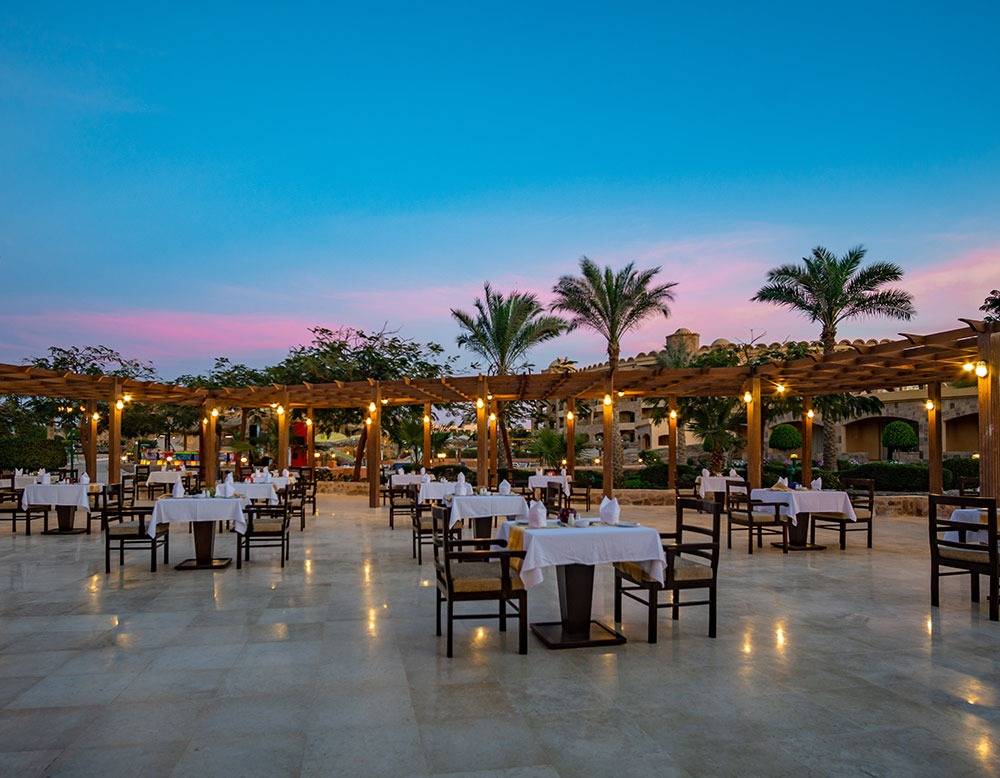 Foto von einem Außenbereich des Utopia Beach Club Hotels mit runden Tischen und Stühlen.