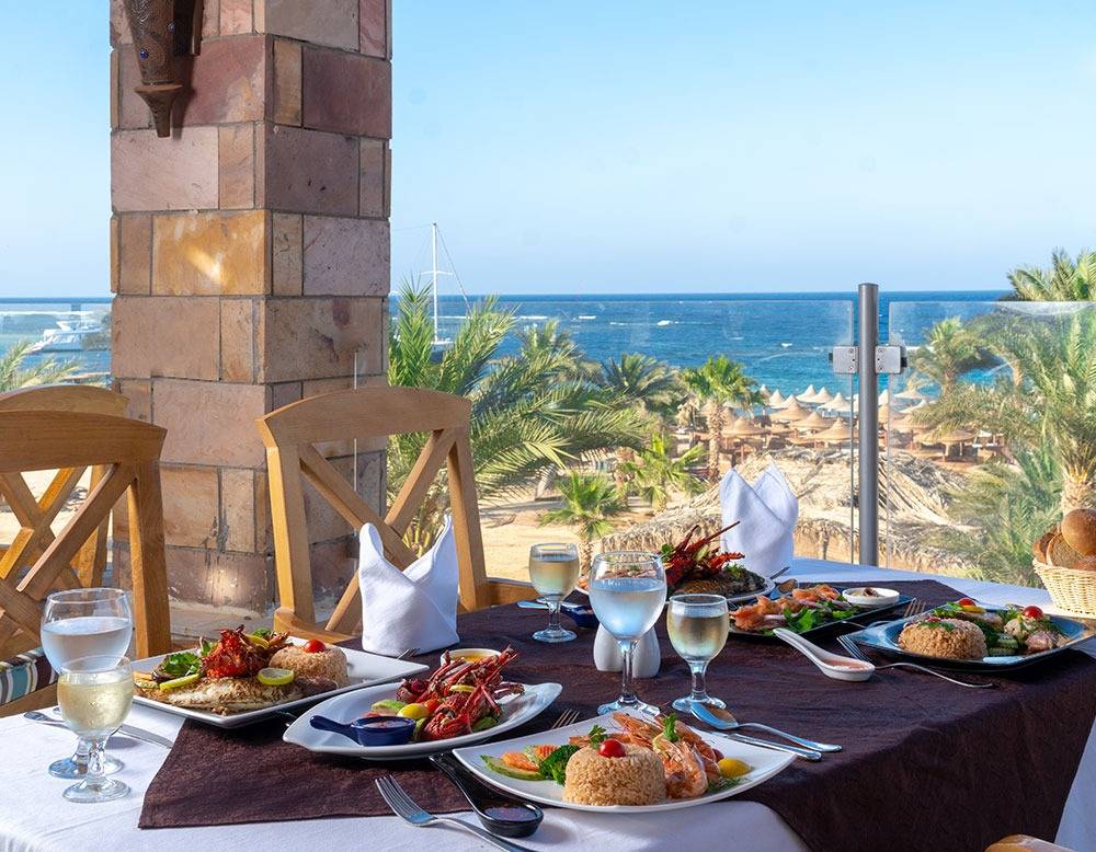 Utopia Beach Club mit Blick auf das Meer und einer servierten Mahlzeit auf dem Tisch.