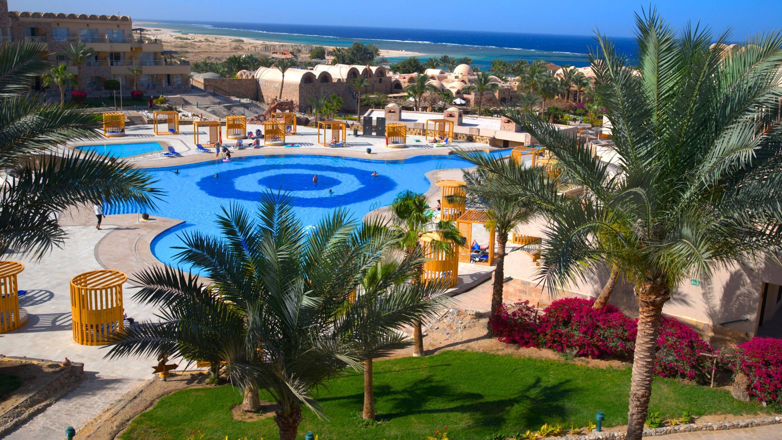 Luftaufnahme des Utopia Beach Club Resorts mit Swimmingpool und Meer im Hintergrund.