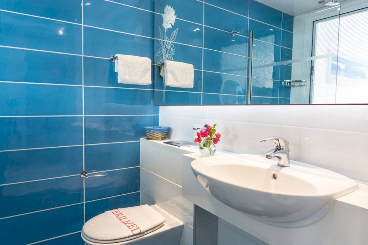 Blaue Fliesen Badezimmer mit Toilette und Waschbecken in einem anonymen Hotel