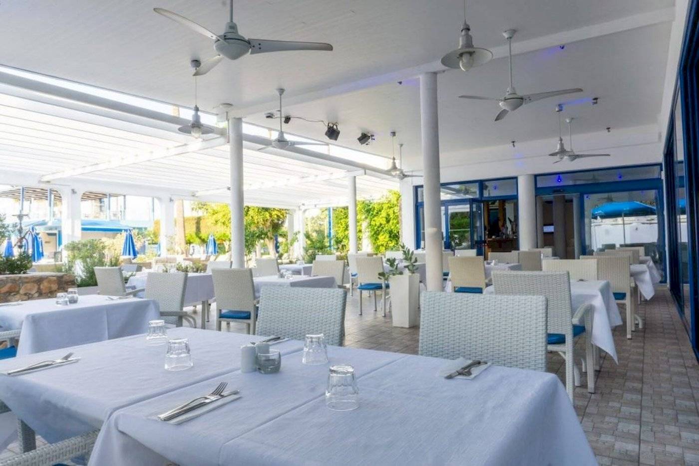 Innenbereich des Restaurants im Anonymous Beach Hotel mit gedeckten Tischen und Stühlen.