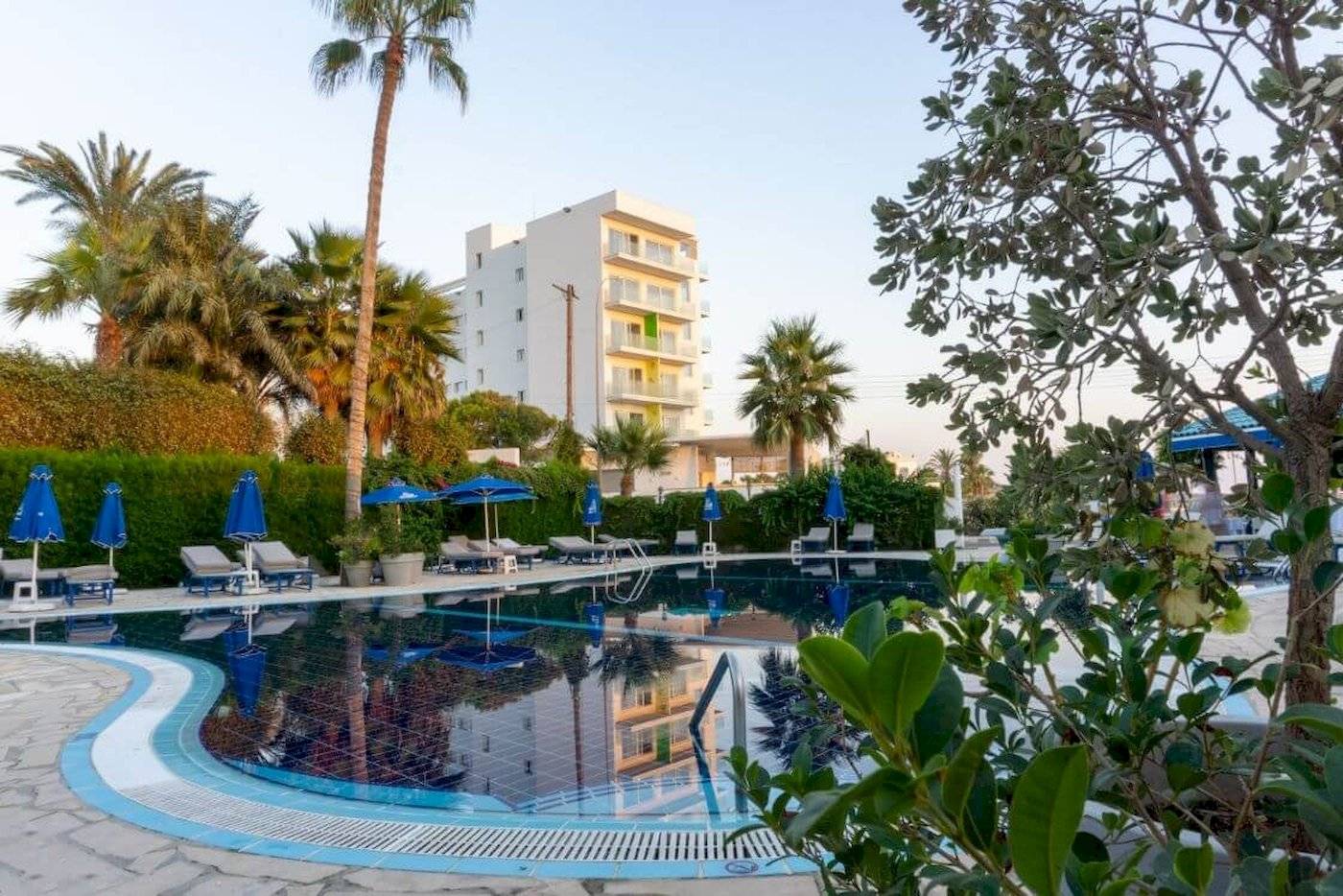 Der Außenpool des Anonymous Beach Hotels mit Lounge-Stühlen, Sonnenschirmen und Palmen.