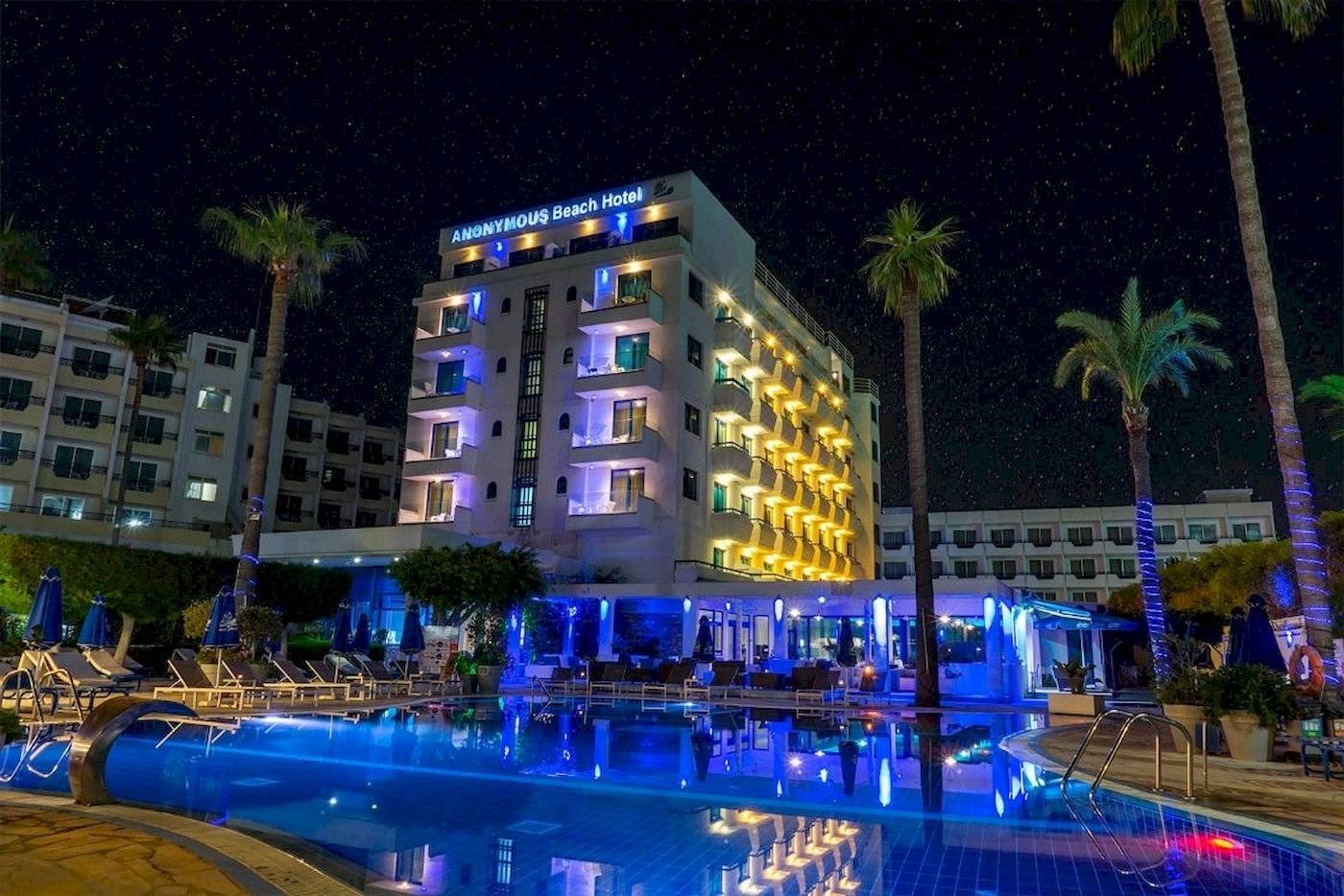 Anonymes Beach Hotel bei Nacht mit beleuchtetem Pool und Loungebereich.