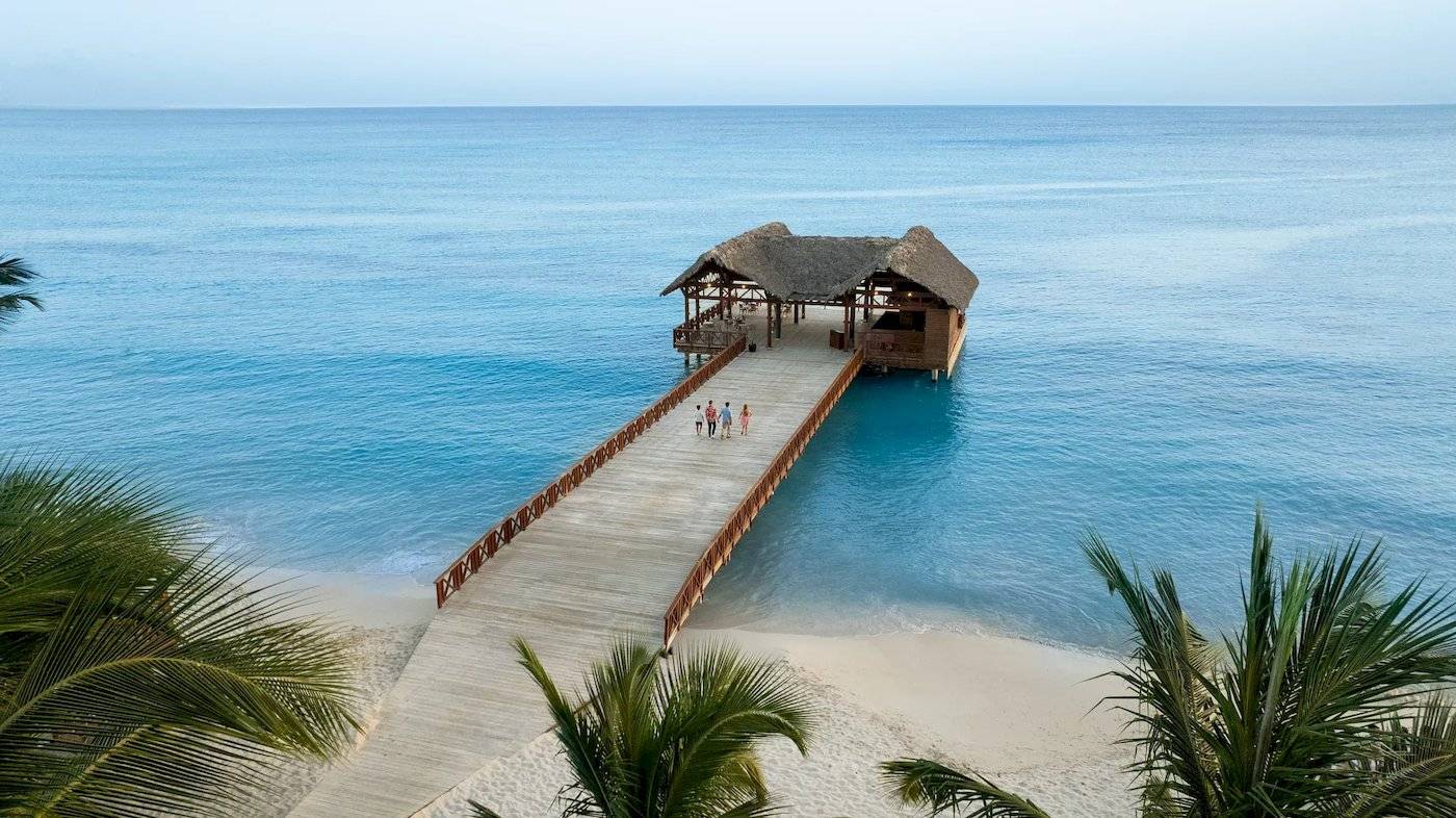 Ein Hotel am Strand der Dominikanischen Republik mit einer Holzbrücke und einer Hütte
