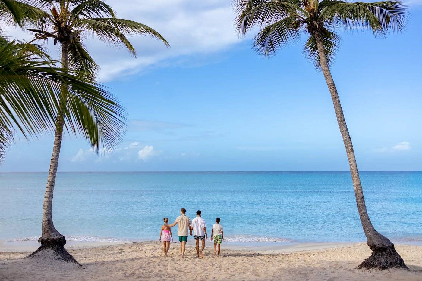 Familie am Strand mit Palmen und blauem Ozean im Hintergrund