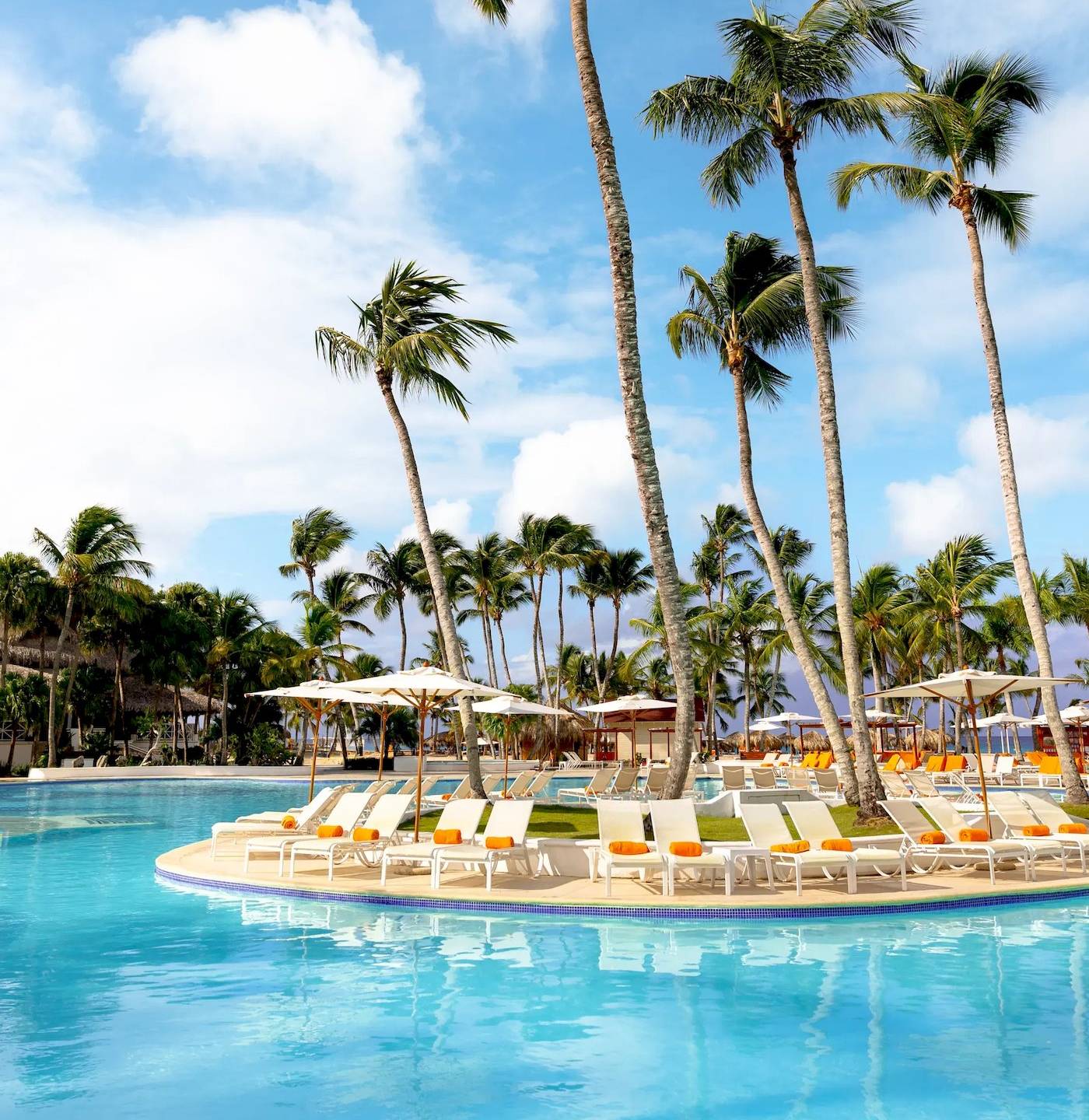 Ein Swimmingpool im Sunscape Dominicus La Romana Hotel mit vielen Palmen und Sonnenliegen.