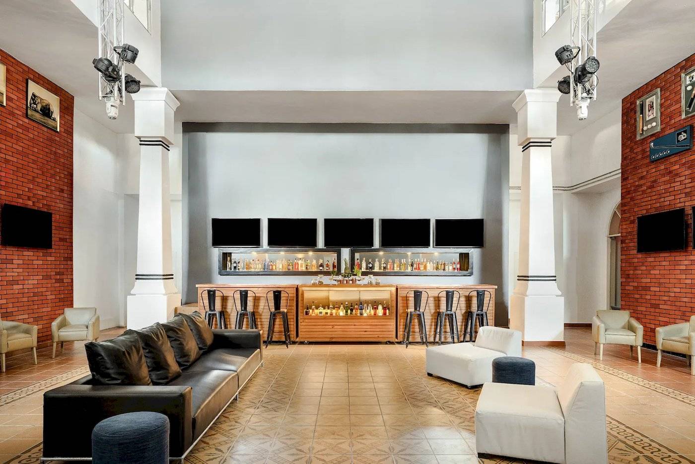 Lobby-Bar-Bereich des Sunscape Dominicus La Romana Hotels mit Bartheken, Sesseln und Fernsehgeräten.