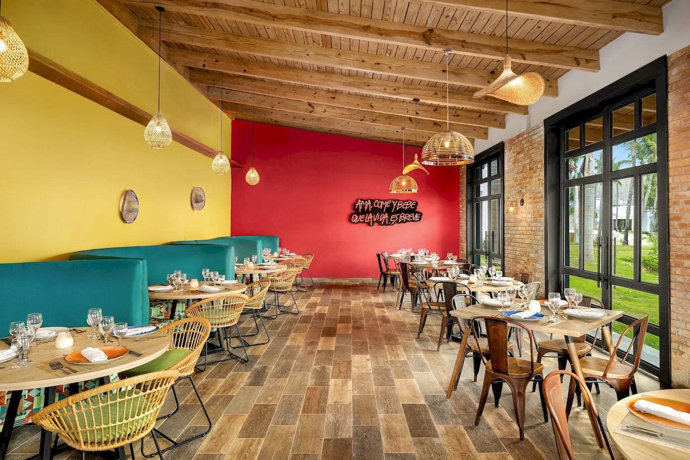 Innenbereich des Restaurants Sunscape Dominicus La Romana mit bunten Wänden, Holzboden und Tischdekoration.