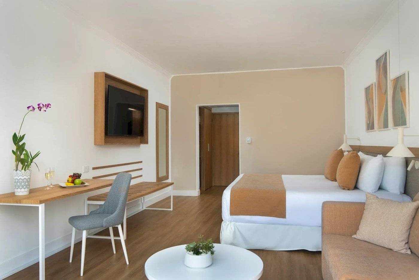 Innenansicht eines Zimmers im Sunscape Dominicus La Romana Hotel mit einem Bett, Schreibtisch, Sofa und Fernseher.