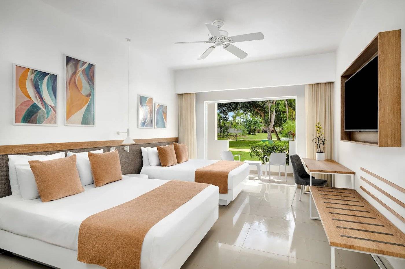 Doppelzimmer im Sunscape Dominicus La Romana mit zwei Betten, Klimaanlage, Fernseher und Fenster zur Terrasse.