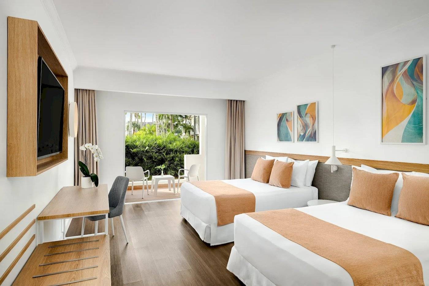 Innenansicht eines Hotelzimmers von Sunscape Dominicus La Romana mit zwei Betten, Schreibtisch und Fernseher.