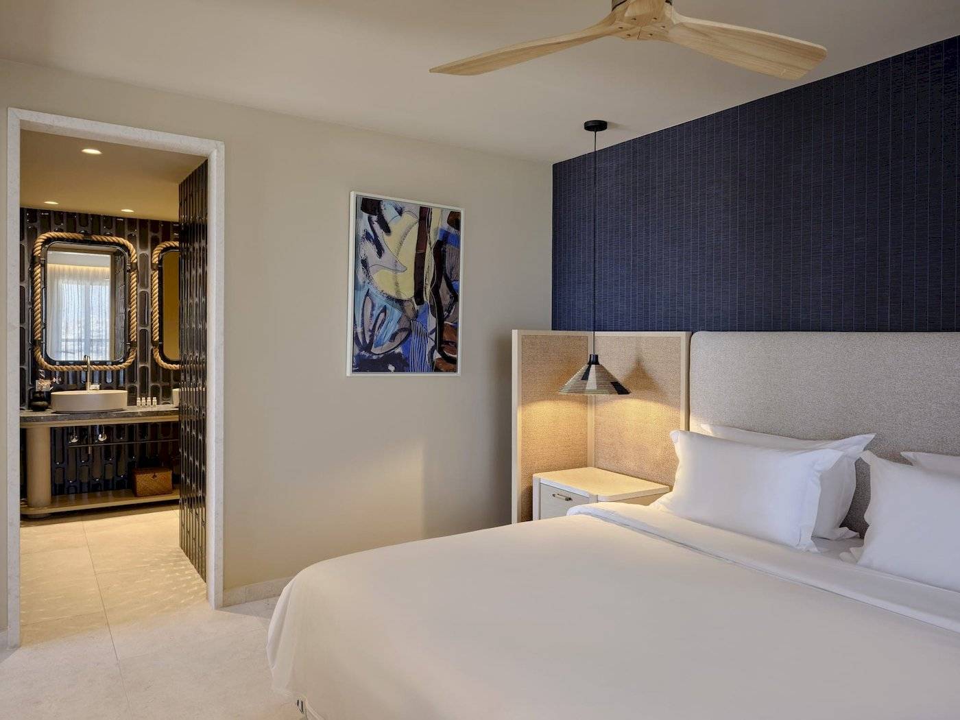 Schlafzimmer im Atlantica Kalliston Resort mit einem großen Bett, weißen Kissen und einer modernen Wanddekoration.