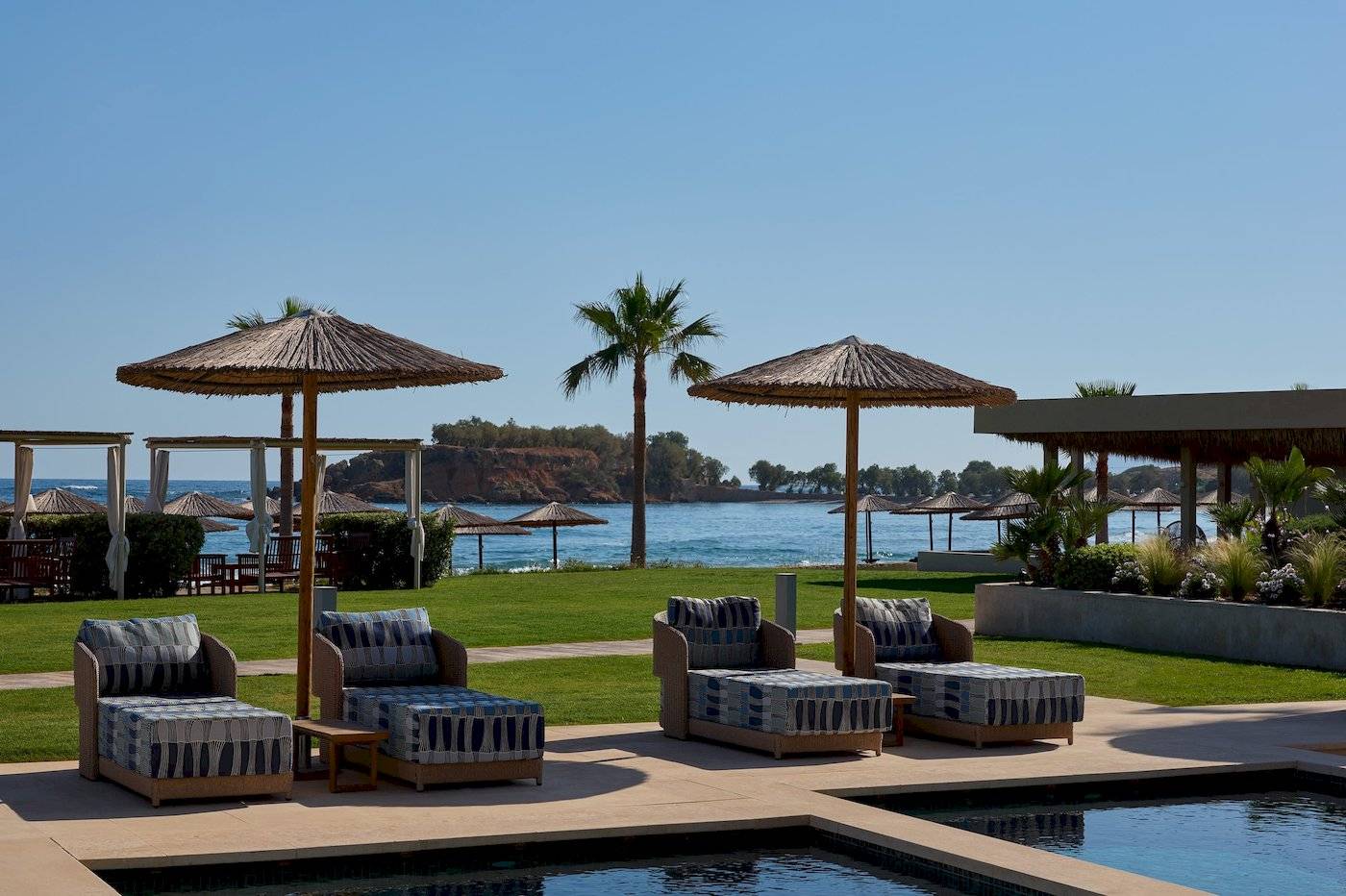 Lounge-Sessel am Pool des Atlantica Kalliston Resorts mit Blick auf das Meer.