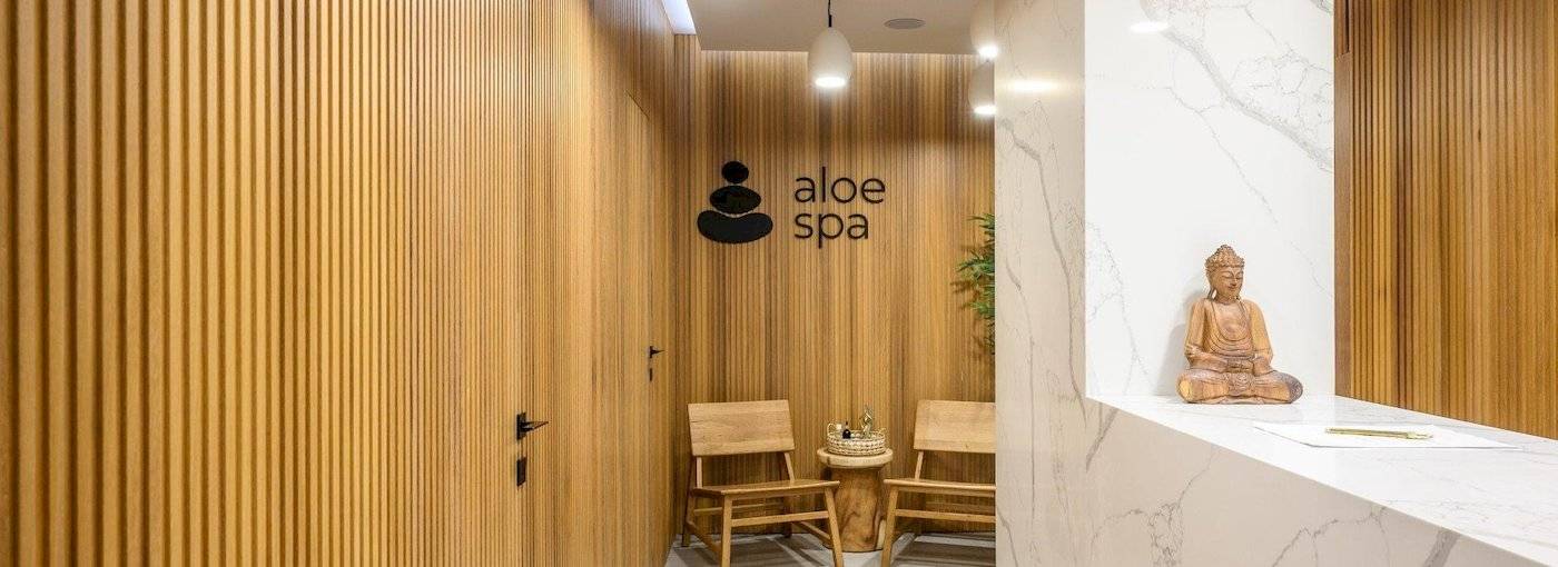 Arminda Hotel & Spa Innenbereich mit Holzwänden, zwei Holzstühlen und einer Buddha-Statue auf der Theke.