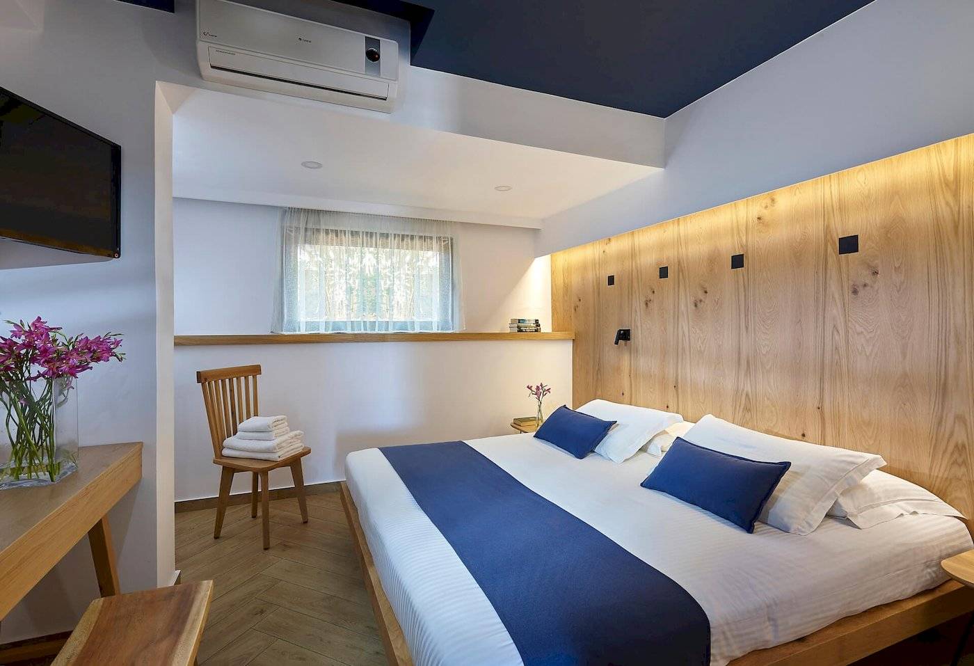 Schlafzimmer im Arminda Hotel & Spa mit einem Bett, Holzwand, Fernseher, Stuhl, und Tisch.