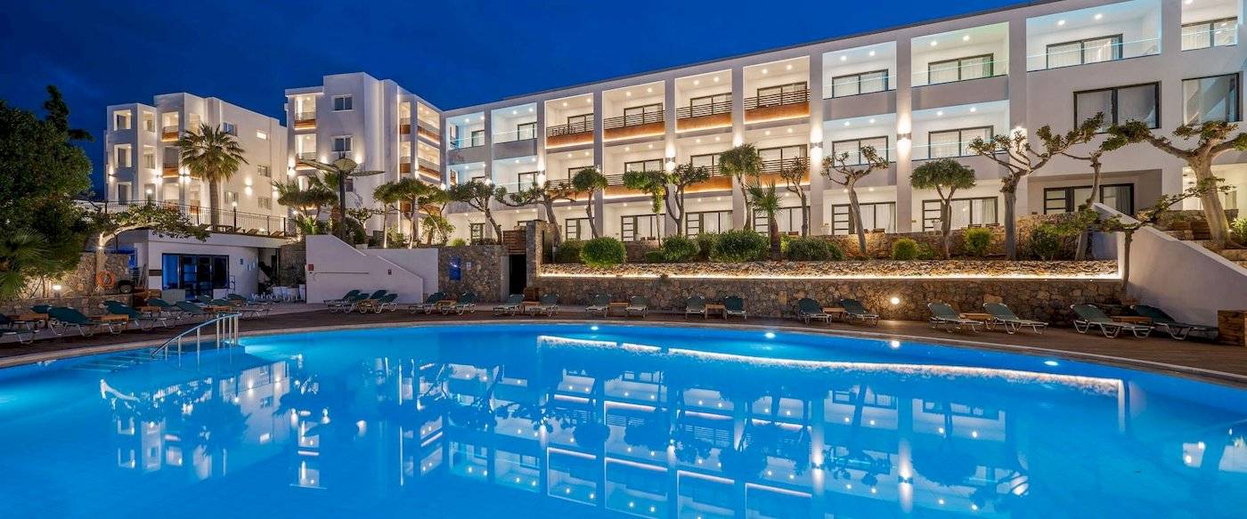 Arminda Hotel & Spa Nachtansicht mit Pool und Liegestühlen.