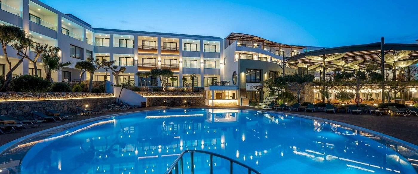 Arminda Hotel & Spa bei Nacht mit beleuchtetem Außenpool und Loungestühlen.