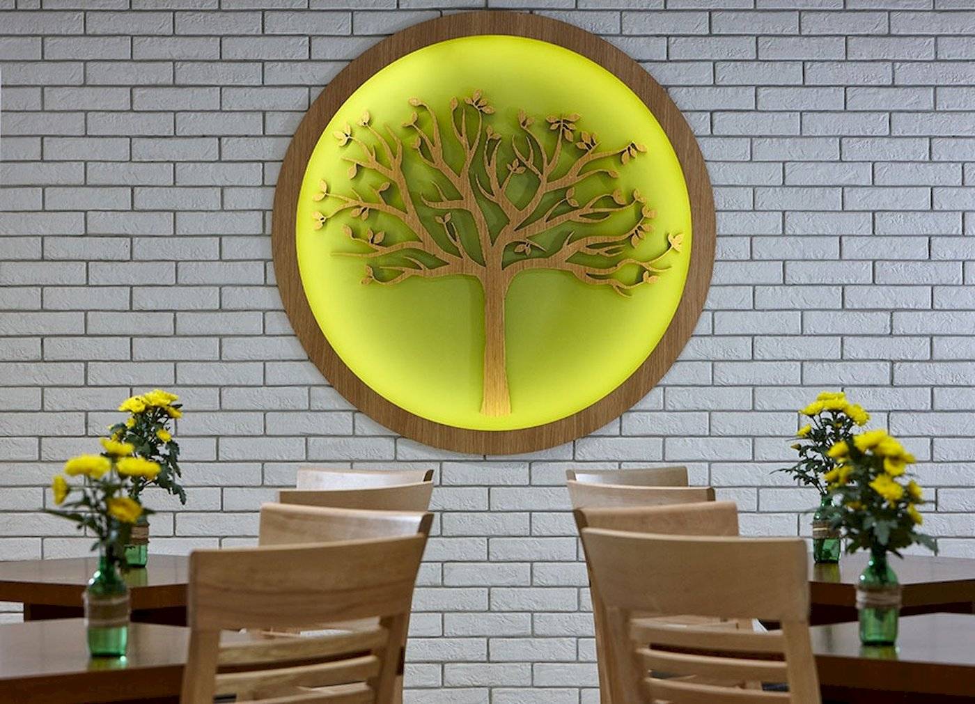 Arminda Hotel & Spa Innenraum mit Baum Wandkunst und Tischen mit Blumenvasen.