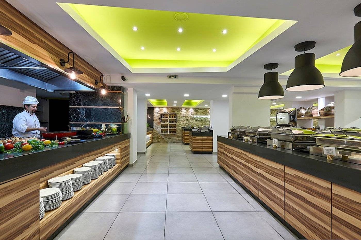 Innenansicht des Restaurants des Arminda Hotel & Spa mit einem Koch, der Gerichte zubereitet.