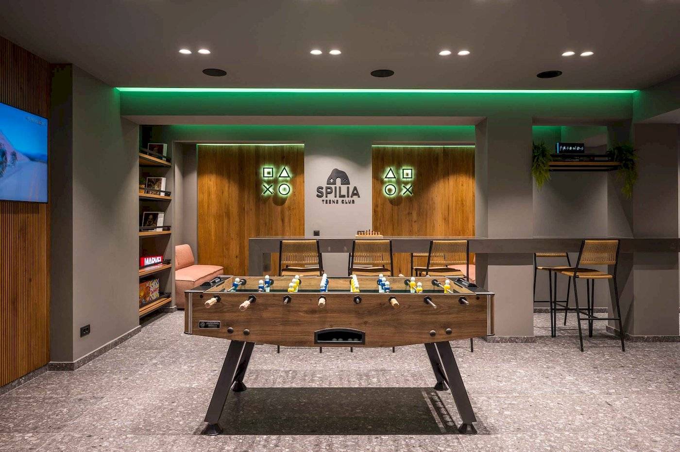 Arminda Hotel & Spa Spilia Teens Club mit Tischfußball, Holztüren und grüner Beleuchtung.