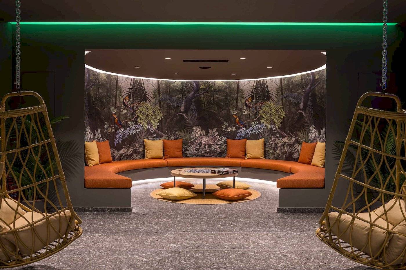 Loungebereich im Arminda Hotel & Spa mit geschwungenem Sofa und tropischem Wandbild.