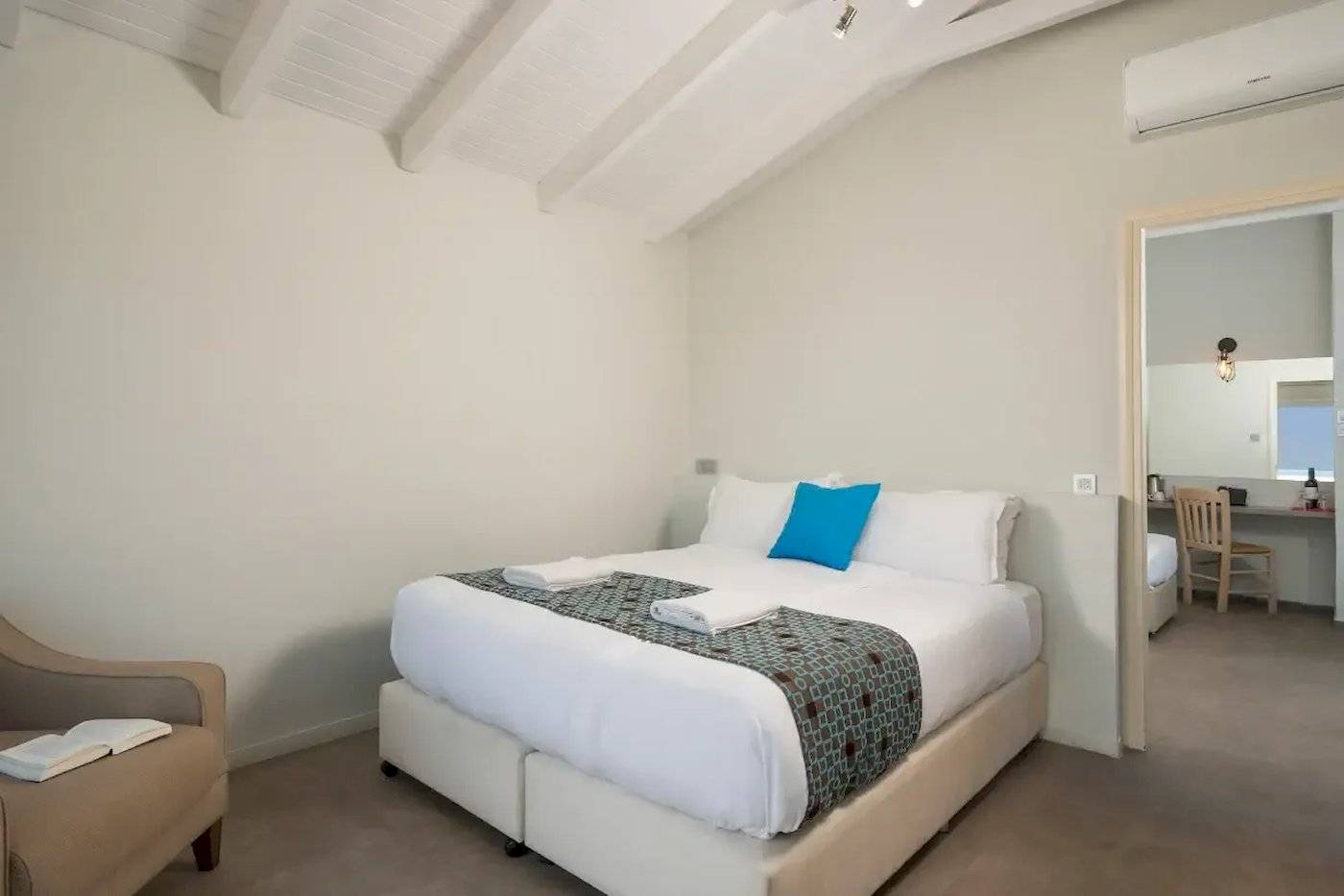 Schlafzimmer im Corissia Beach Hotel mit weißem Bett, blauem Kissen und Klimaanlage.