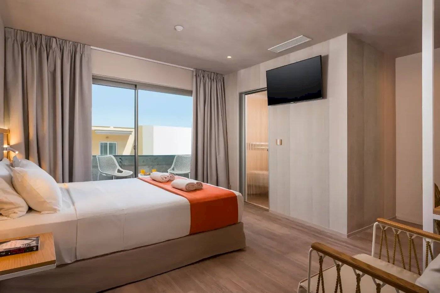 Innenansicht eines Doppelzimmers im Corissia Beach Hotel mit Bett, Fernseher und Balkon.