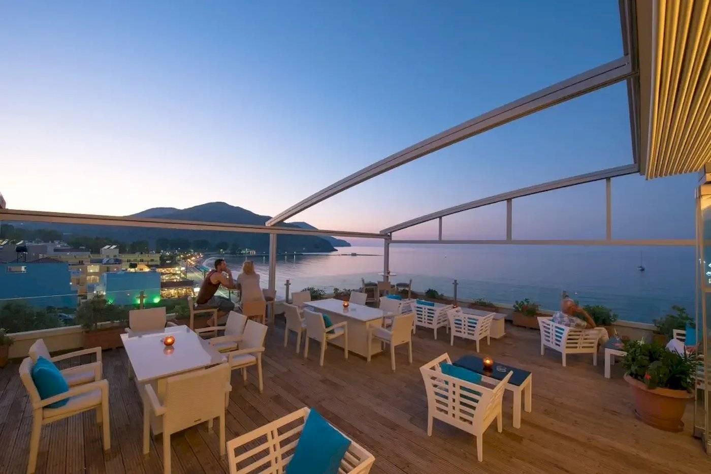 Abendliche Terrasse des Corissia Beach Hotels mit Blick auf das Meer und die Stadt.
