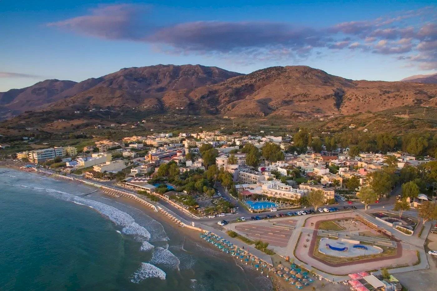 Luftaufnahme des Corissia Beach Hotels mit Blick auf den Strand, die Stadt und die Berge.