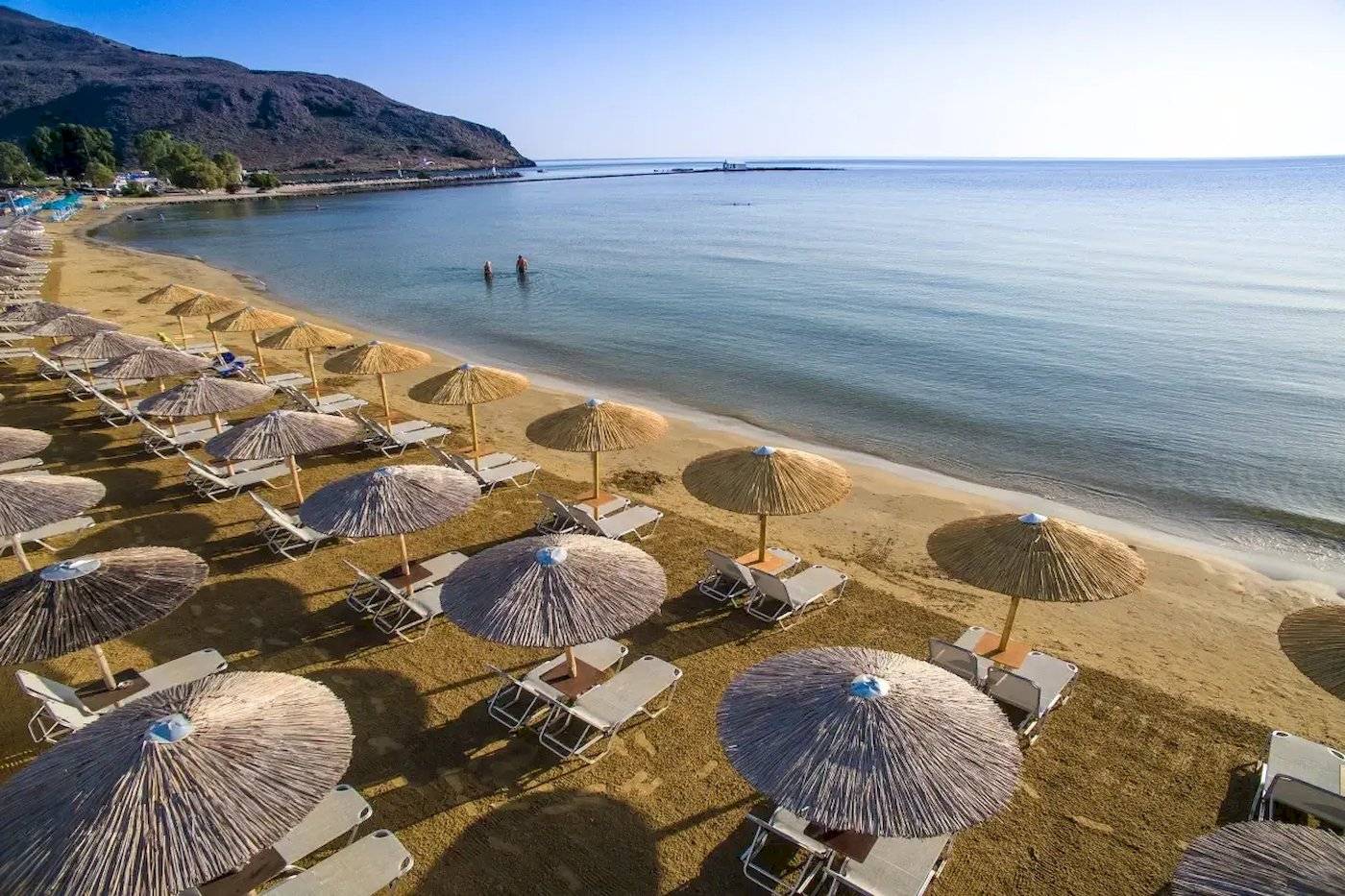 Luftaufnahme des Corissia Beach Hotels mit vielen Liegestühlen und Sonnenschirmen am Strand