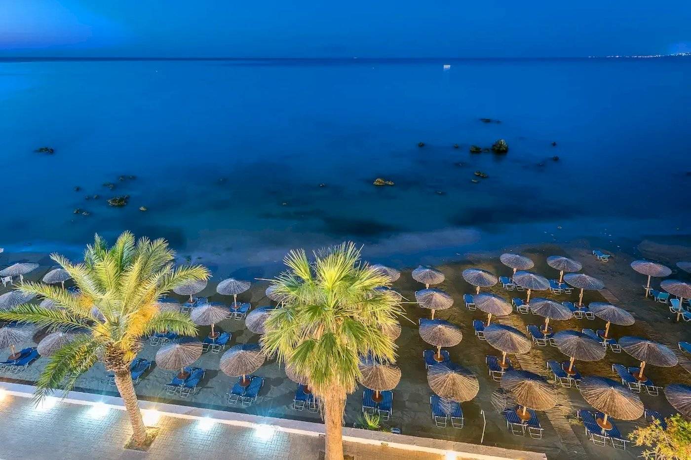 Abendblick auf den Strand des Corissia Beach Hotels mit vielen Sonnenschirmen und Liegen.
