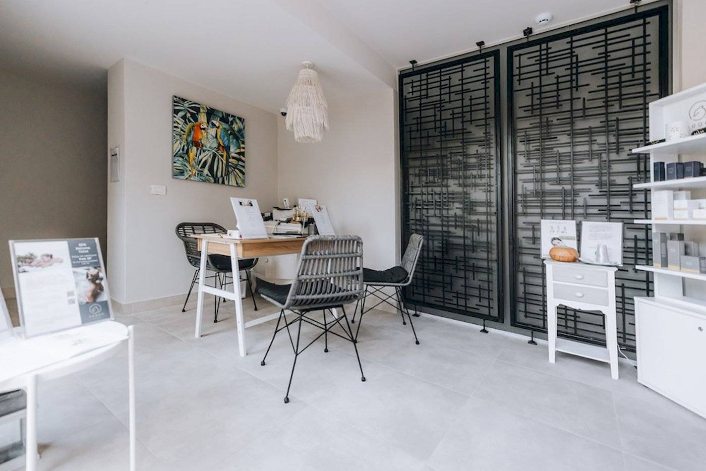 Ein elegantes Spa-Behandlungszimmer mit Tisch, Stühlen und einer bunten Wandmalerei.