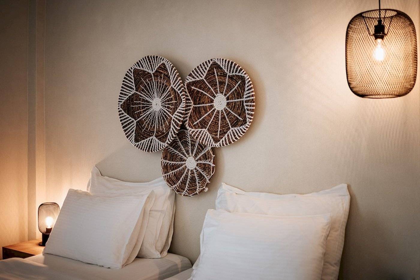 Schlafzimmer im Eliros Mare Hotel mit zwei Betten, weißen Kissen und dekorativen Wandkörben.