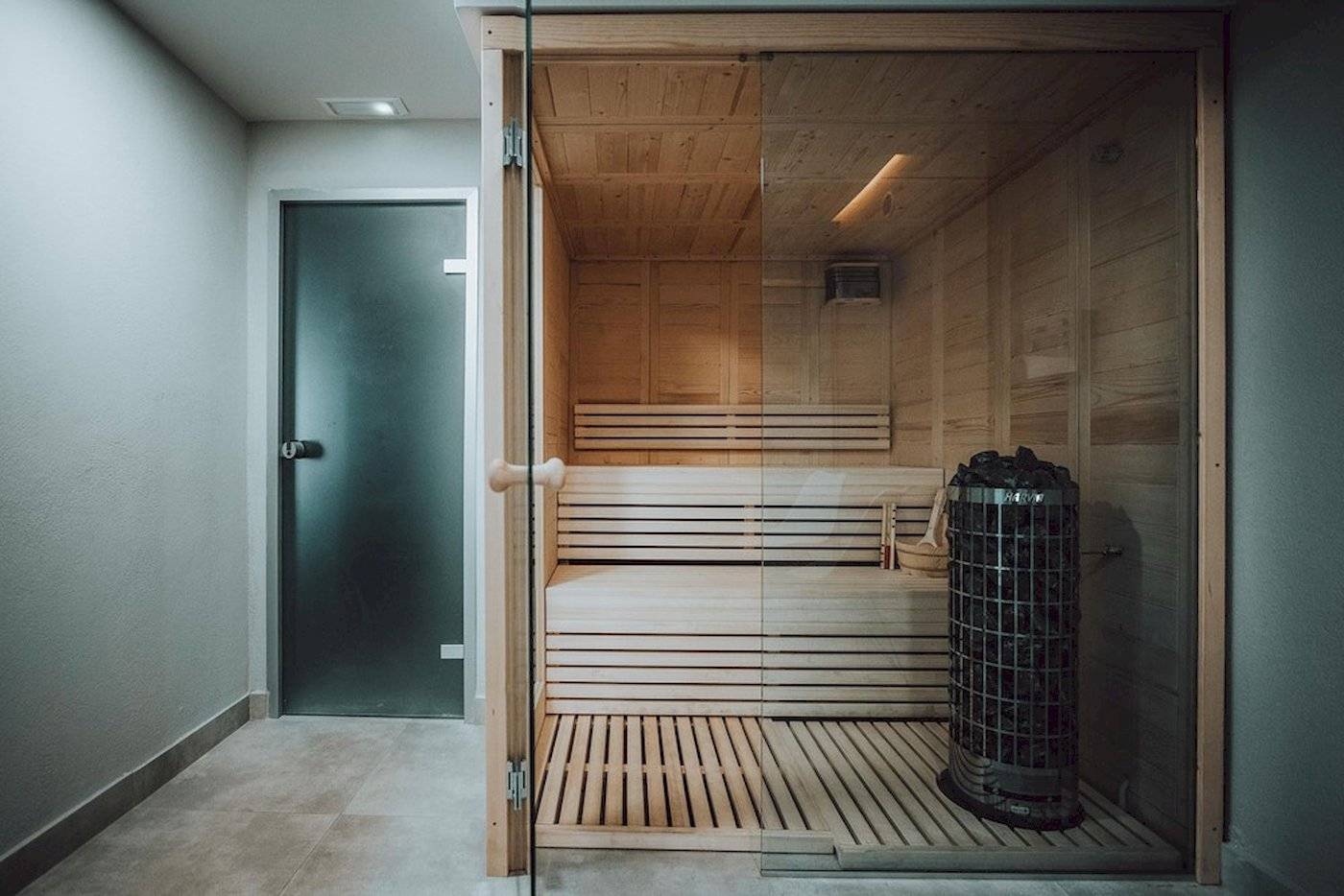 Eine hölzerne Sauna mit offenem Eingang und einer Heizeinheit in einem modernen Hotel.