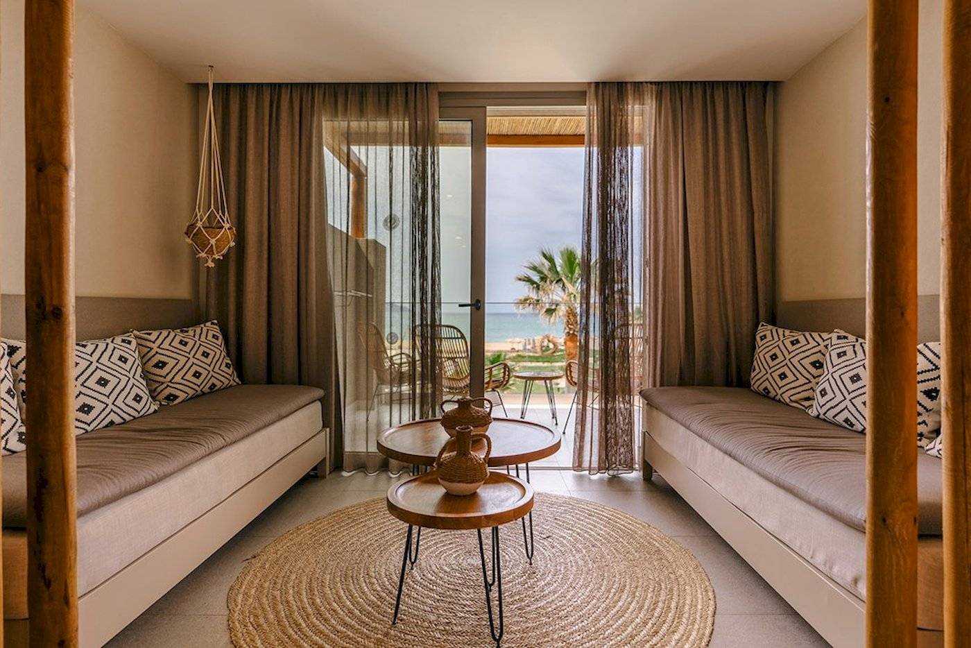 Innenraum des Eliros Mare Hotels mit Blick auf das Meer und einem Wohnzimmer mit zwei Sofas und Tisch.