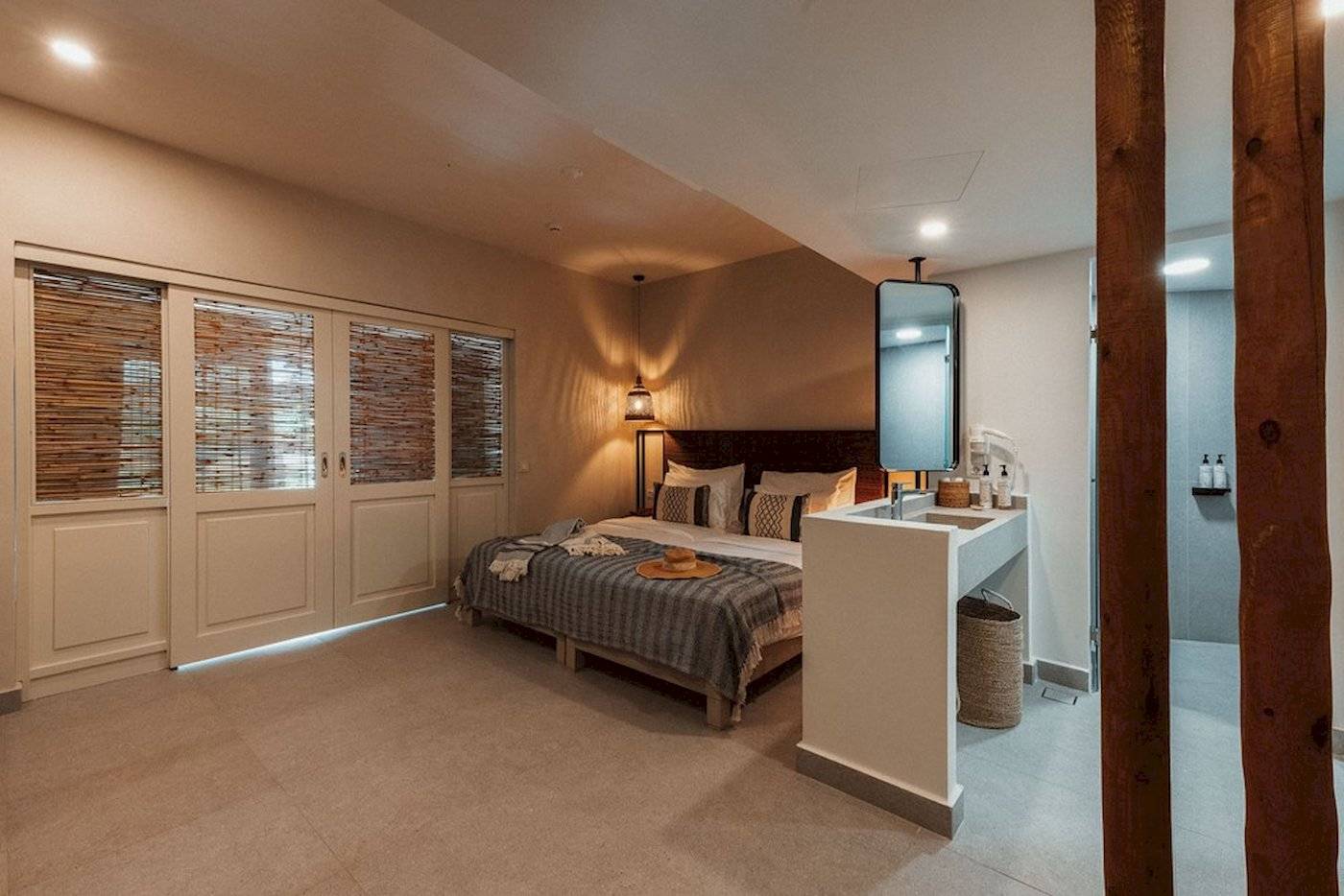 Innendesign eines Schlafzimmers im Eliros Mare Hotel mit Bett, Spiegel und Badezimmer.