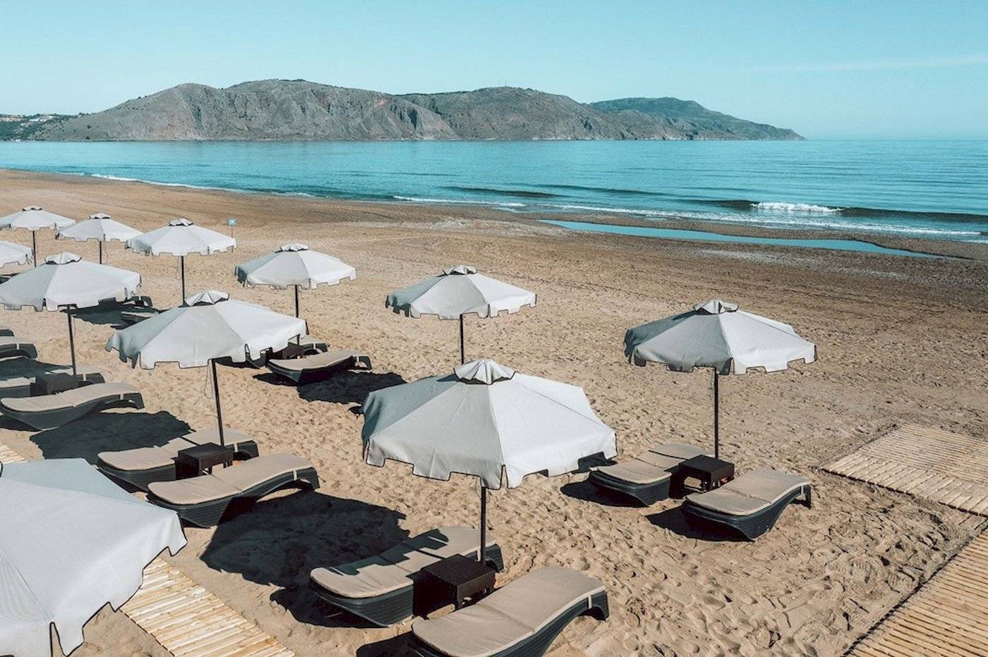 Strand des Eliros Mare Hotels mit Sonnenschirmen und Liegestühlen am Meer