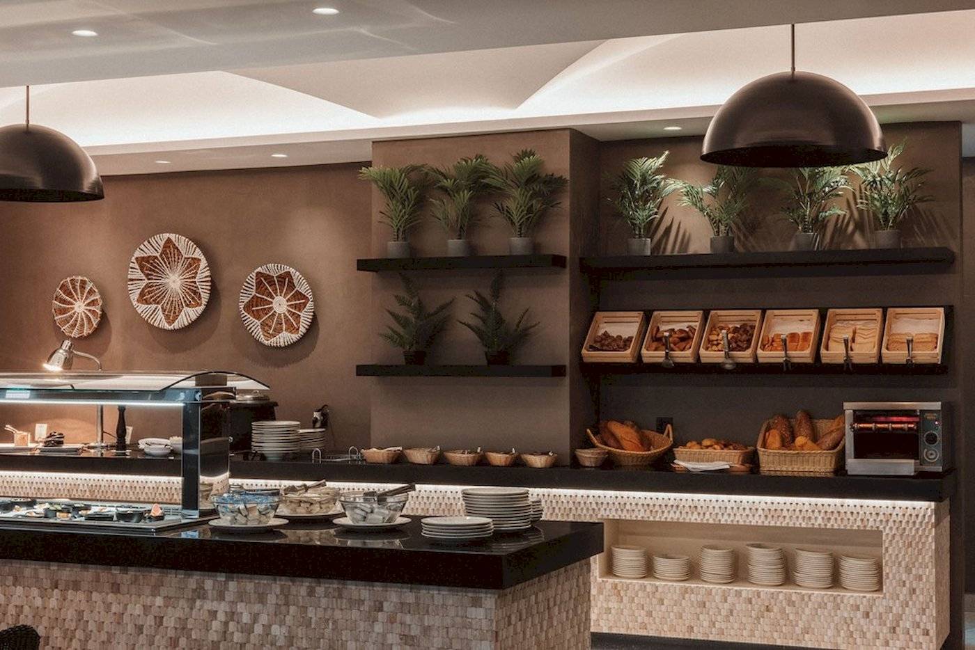 Frühstücksbuffet im Eliros Mare Hotel mit Speisen, Tellern und Pflanzen.