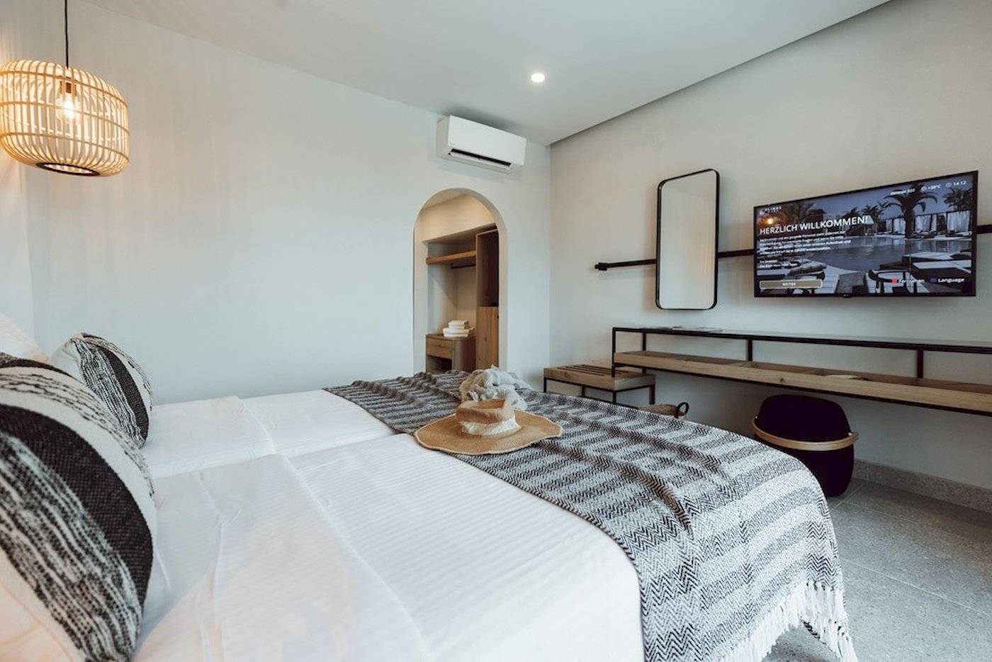 Schlafzimmer im Eliros Mare Hotel mit Bett, Fernseher, Spiegel und Wandmontage.