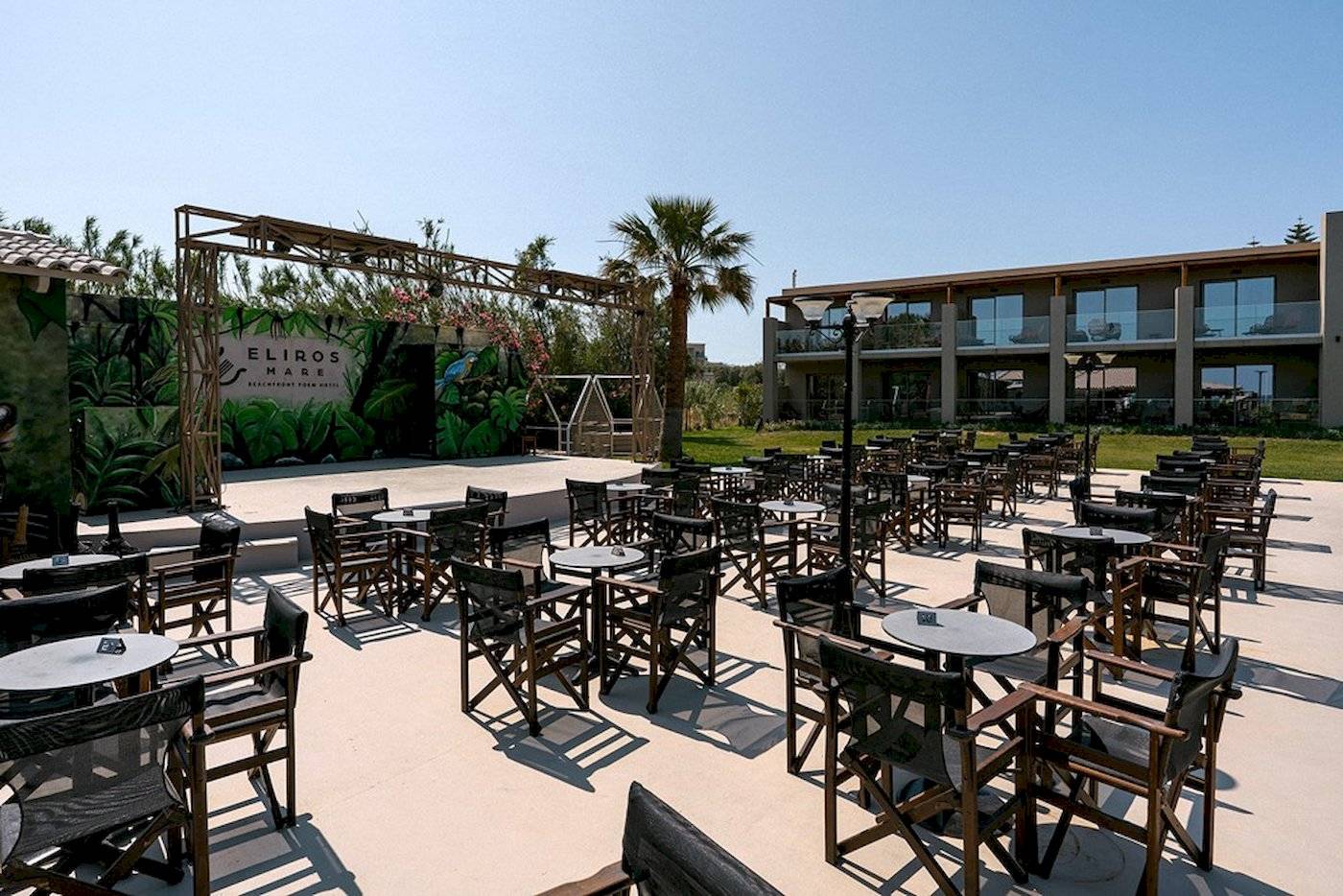 Terrasse des Eliros Mare Beachfront Hotels mit vielen Tischen und Stühlen.