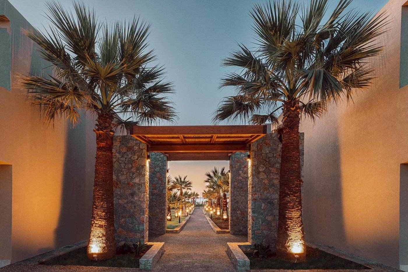 Eingang zum Eliros Mare Hotel mit Palmen und beleuchtetem Weg