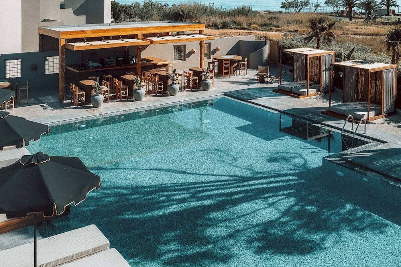 Außenbereich des Eliros Mare Hotels mit Pool, Bar und Sonnenliegen.