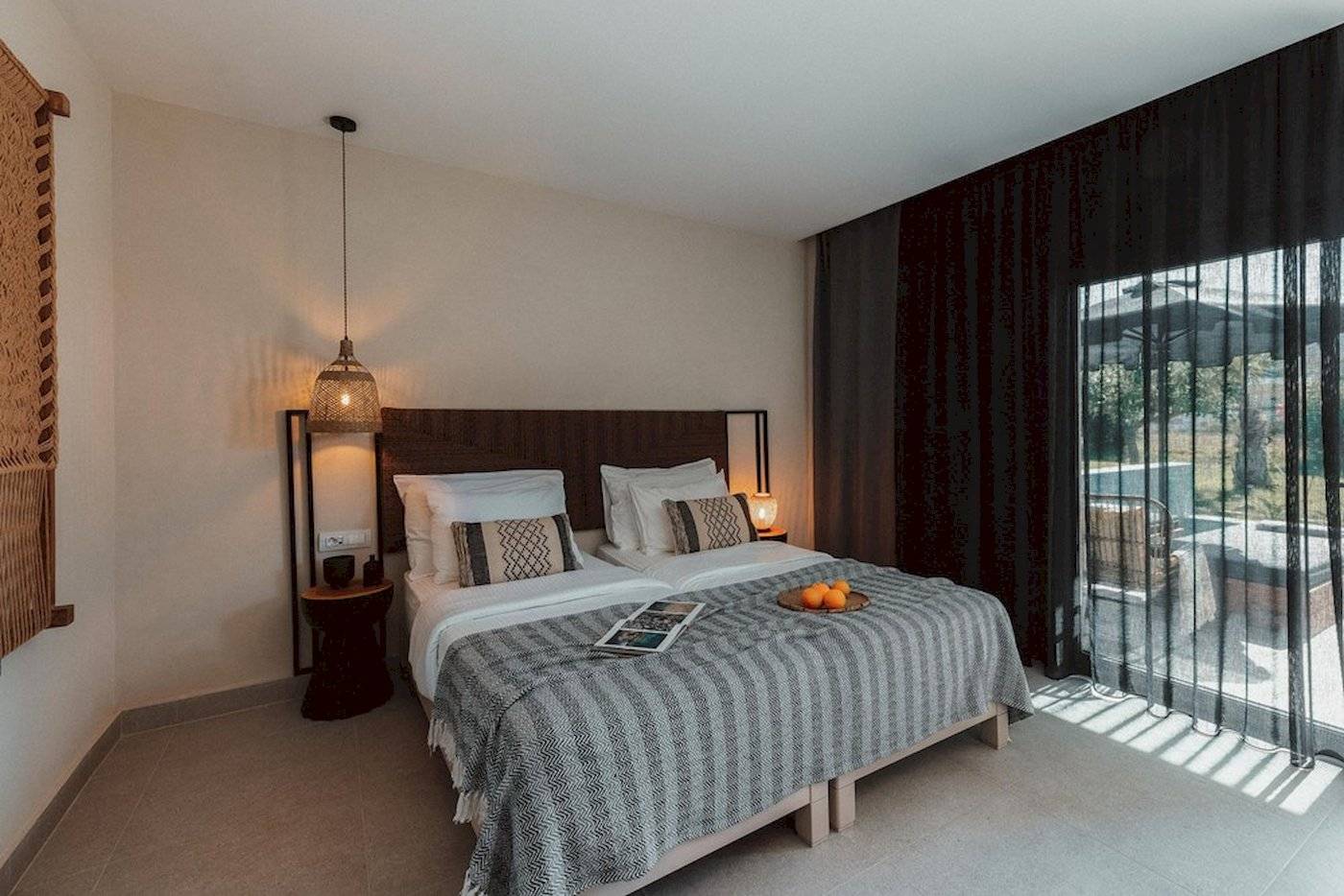 Schlafzimmer im Eliros Mare Hotel mit zwei Betten, Kissen, Decken und einem Fenster mit Blick auf einen Pool.