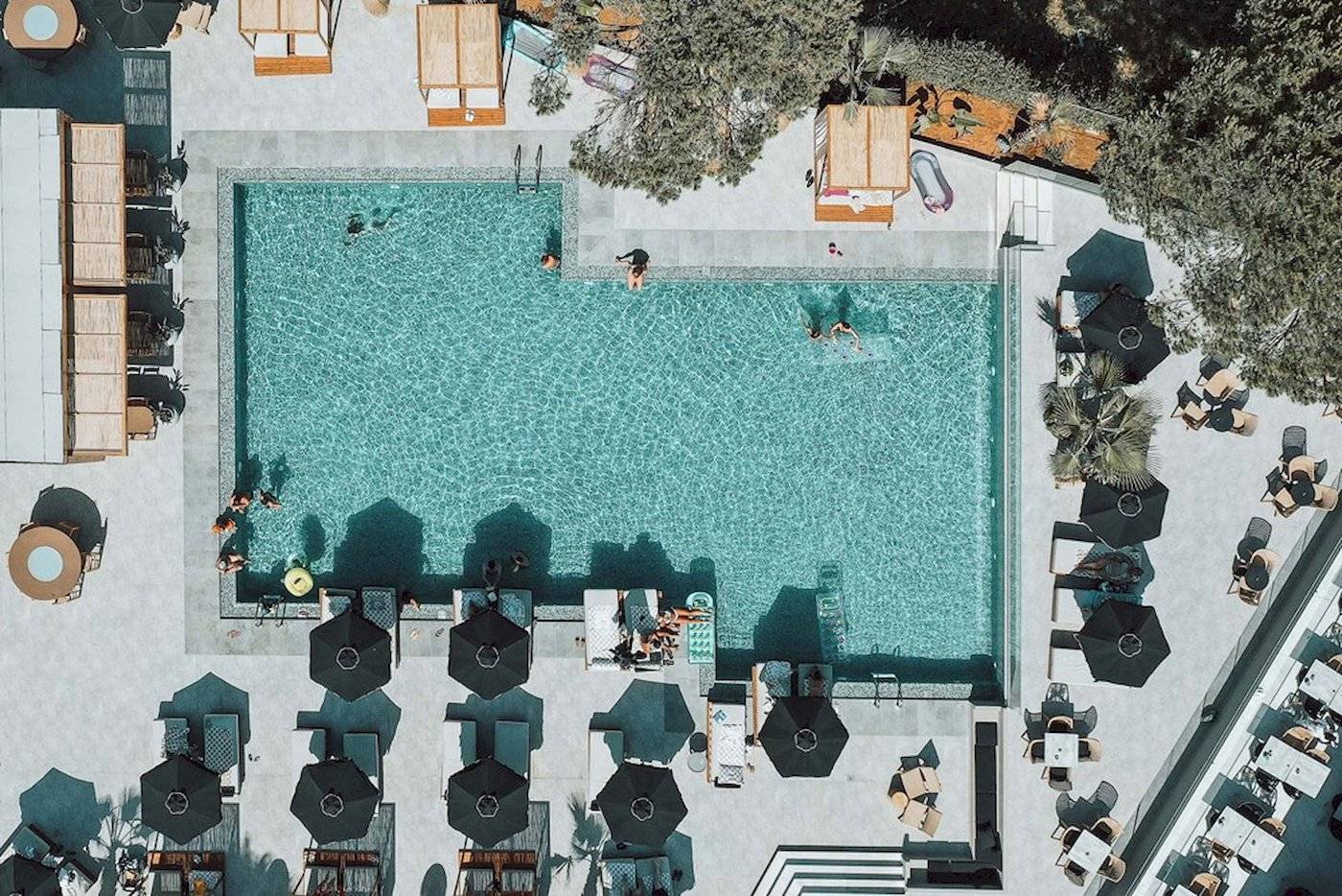 Luftaufnahme des Pools im Eliros Mare Hotel mit Gästen und Sonnenschirmen.
