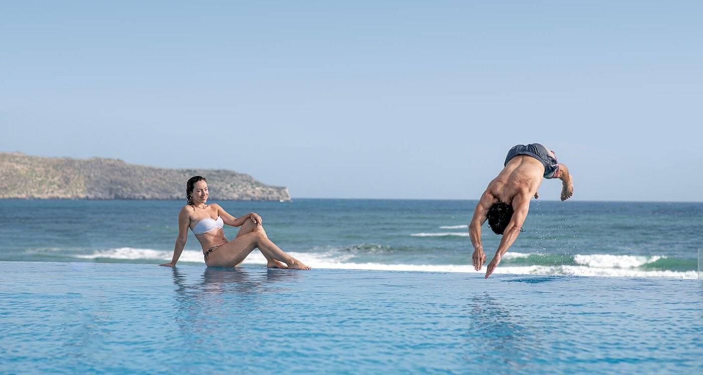 Mann springt ins Wasser im Außenpool am Cretan Dream Resort & Spa.